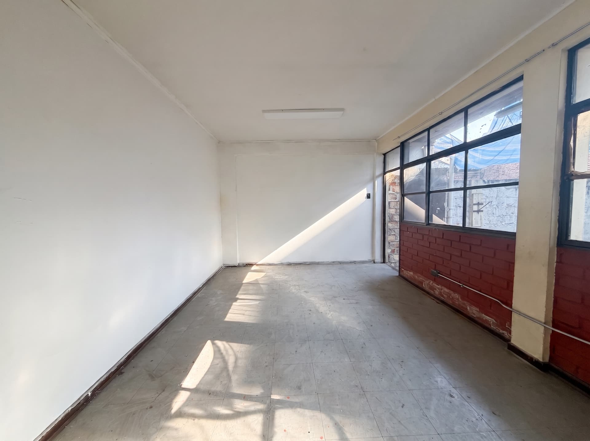Espacio 7 en la sede Salvador, Ñuñoa — Sala amplia y luminosa, con ventanal completo, muro de ladrillo y luz directa. Ideal para confección, diseño o fotografía de producto.